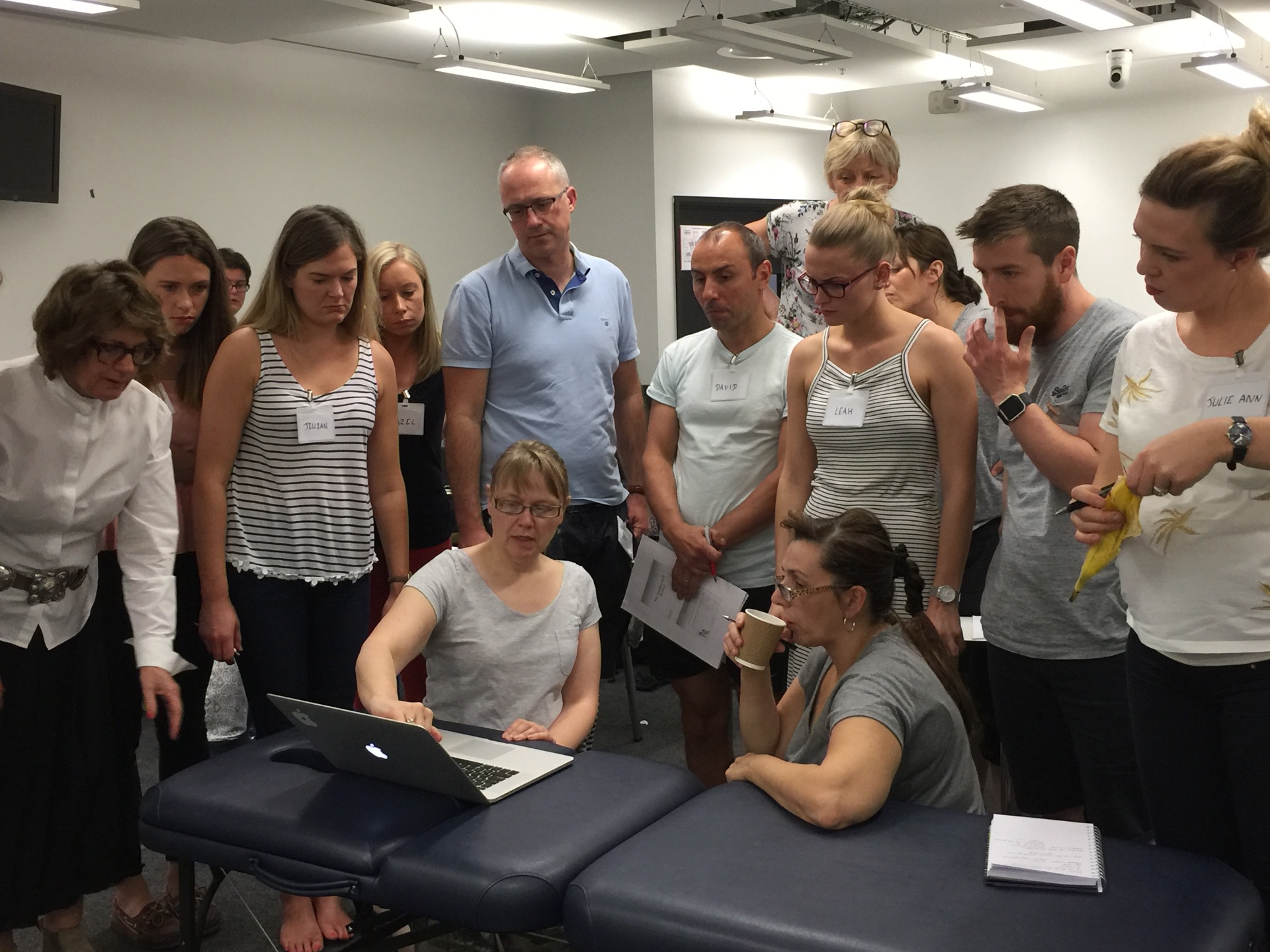 Sarah Key teaching a hands-on workshop with physiotherapists gathered around a treatment table